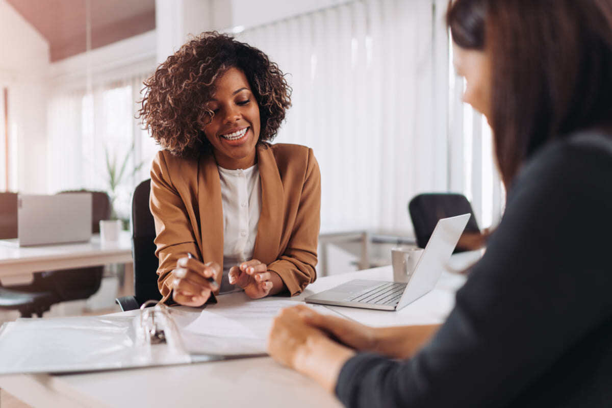 Two people in professional clothing talking at a table