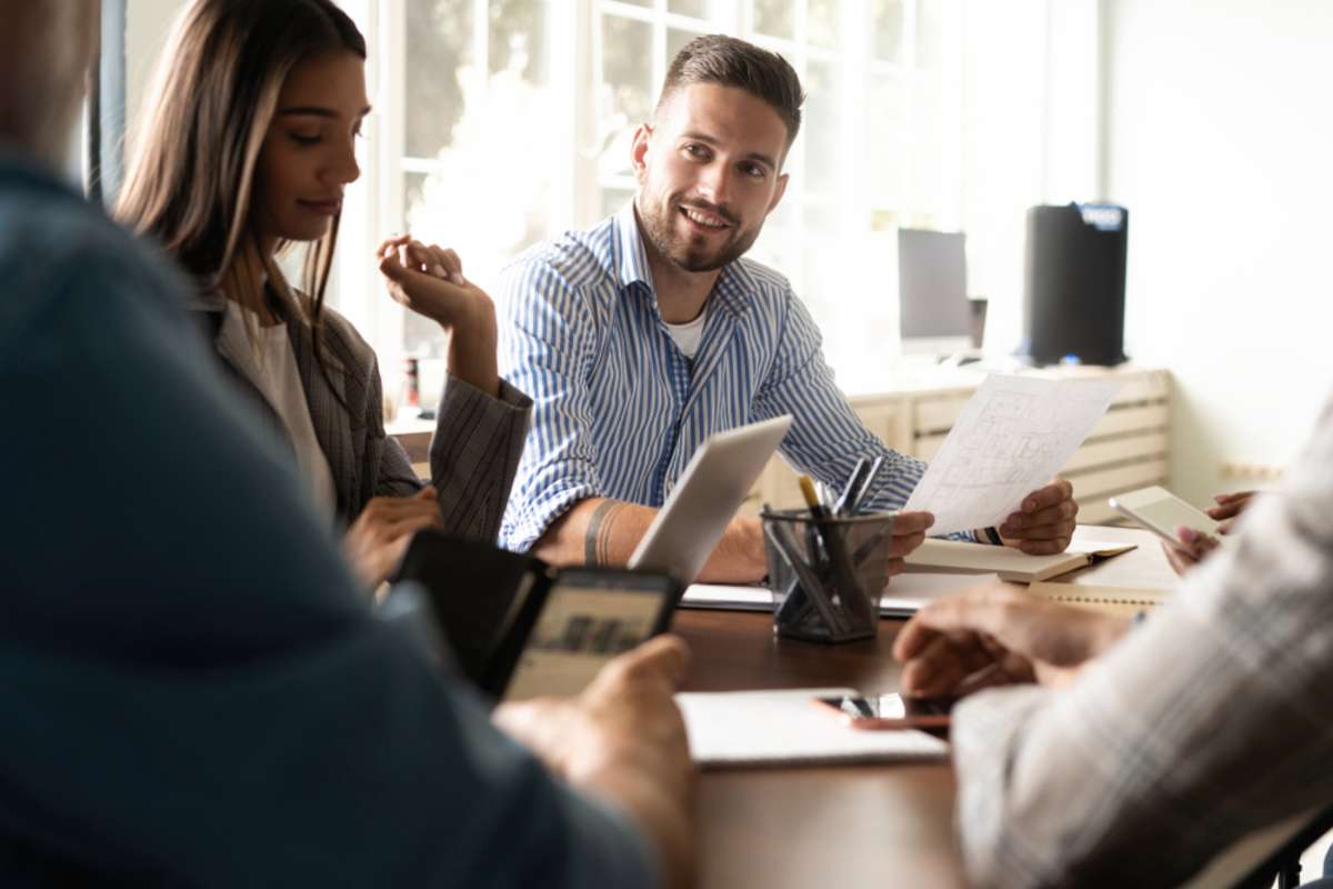 Group of young business people working and communicating while sitting at the office desk together