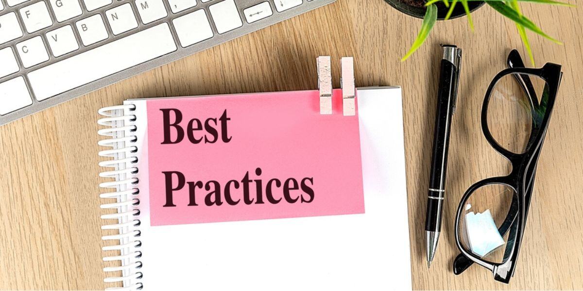 BEST PRACTICES text pink sticky on a notebook with keyboard, pen and glasses